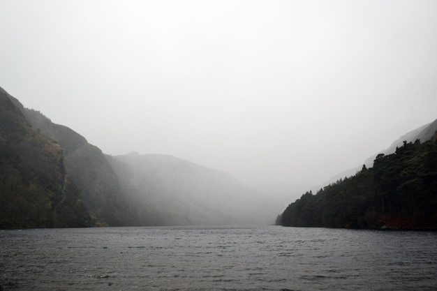 Lac entouré de collines sous le ciel gris brumeux