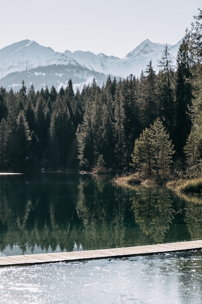 Lac entouré de montagnes couvertes de neige et d'une forêt d'arbres se reflétant sur l'eau