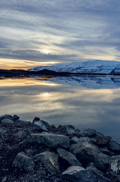 Photo gratuite lac givré scandinave près des hautes terres formant un paysage hivernal nordique au coucher du soleil, une grande étendue d'eau et des montagnes enneigées dans un paysage islandais. champs gelés dans une campagne spectaculaire.