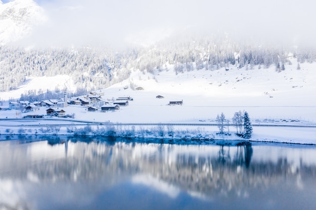 Lac par les collines couvertes de neige capturé un jour brumeux