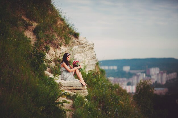 Lady avec bouquet rouge s&#39;assoit sur la colline verte