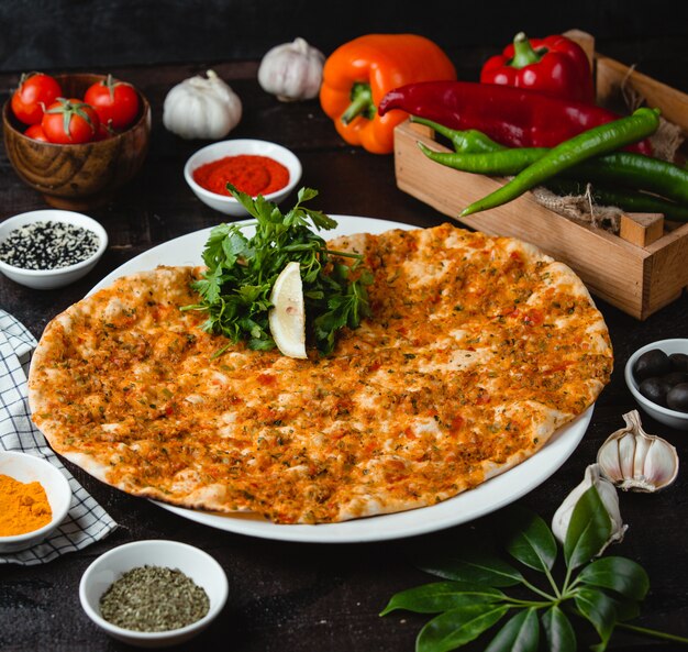 Lahmajun turc avec de la viande farcie, une tranche de citron et des herbes