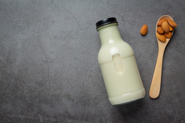 Lait d'amande en bouteille aux amandes sur fond sombre