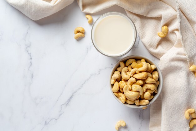 Lait de cajou végétalien en verre avec des noix de cajou sur fond de marbre