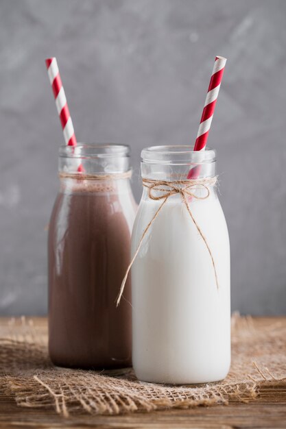 Lait nature et chocolat au lait en bouteilles avec des pailles