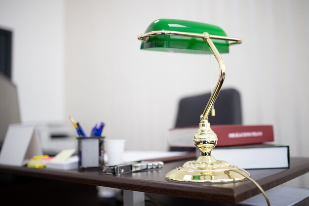 Lampe de bureau verte dans un bureau avec des livres et des fichiers