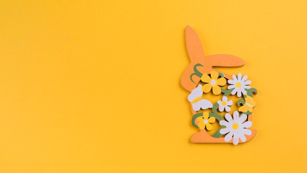 Lapin en bois avec des fleurs sur une table jaune