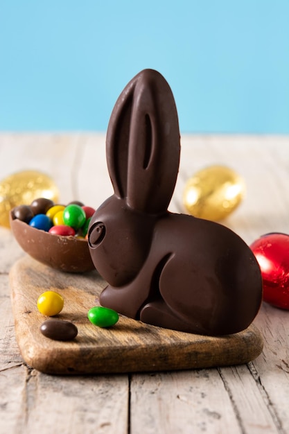 Lapin en chocolat de Pâques et oeufs colorés sur table en bois