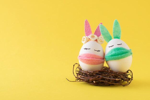 Composition De Paques Avec Un Plateau D Oeufs Un Masque Medical Avec Un Visage Et Des Oreilles De Lapin De Paques Peint Parmi Les Confettis Close Up Photo Gratuite