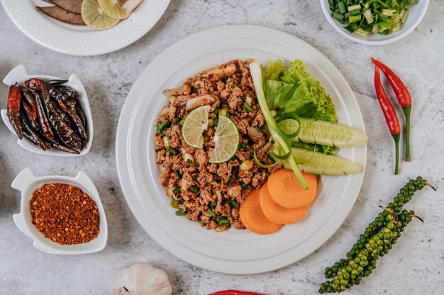 Larb de porc avec carotte, concombre, lime, oignon nouveau, piment, poivre fraîchement moulu et laitue.