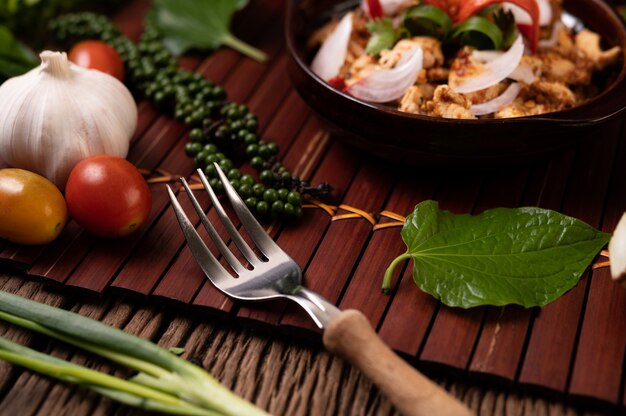 Larb de poulet dans l'assiette Avec piments séchés, tomates, oignons nouveaux et fourchette à laitue.