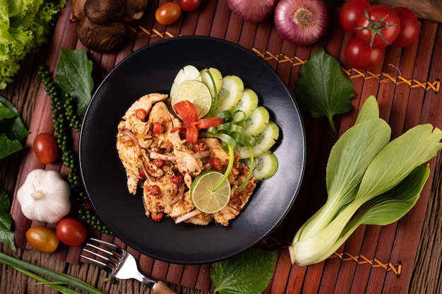 Larb de poulet dans l'assiette avec piments séchés, tomates, oignons nouveaux et laitue