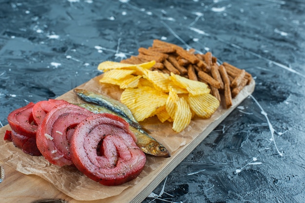 Lard de porc, poisson, frites et chapelure sur une planche à découper , sur la table bleue.