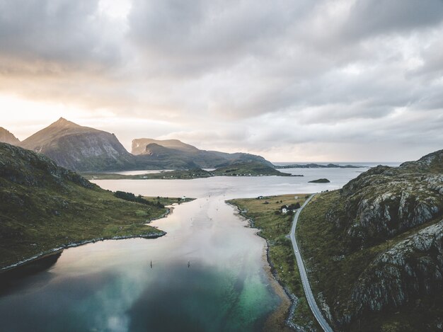 Large paysage tourné de la mer entourée de montagnes sous un ciel rosé avec des nuages