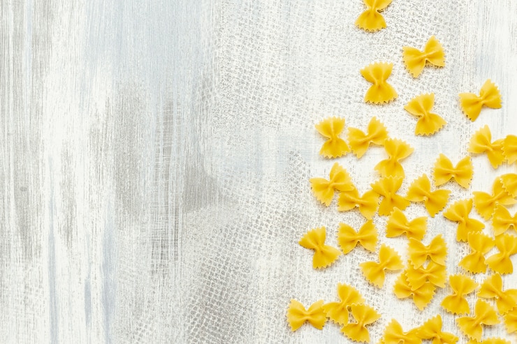 Photo gratuit lay plat de pâtes farfalle sur fond en bois avec espace de copie