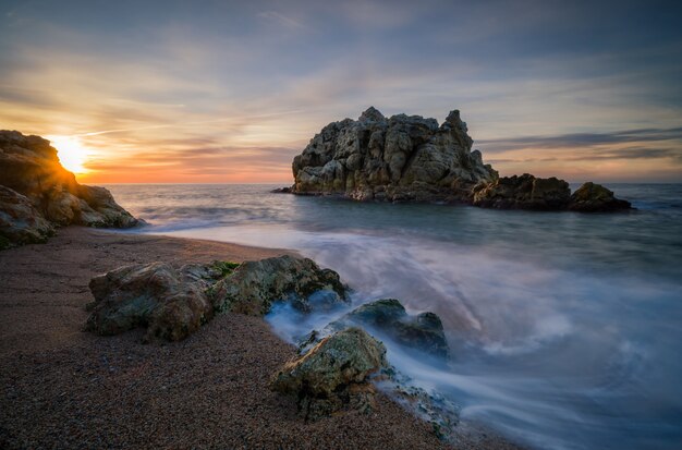 Île rocheuse près de la plage d'une belle mer au coucher du soleil