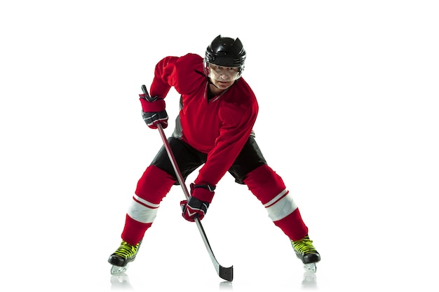 Photo gratuite leader. joueur de hockey masculin avec le bâton sur un court de glace et un mur blanc. sportif portant de l'équipement et un casque pratiquant. concept de sport, mode de vie sain, mouvement, mouvement, action.