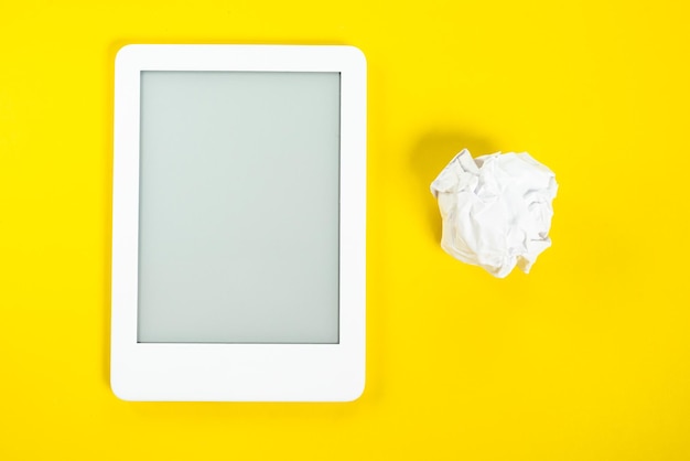 Lecteur d'ebook sur fond jaune avec boule de papier à côté