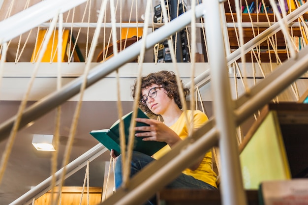 Lecture femme assise dans les escaliers avec un livre