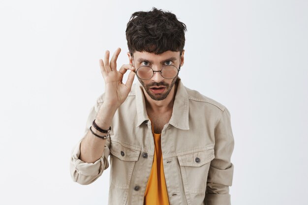 Élégant barbu choqué posant contre le mur blanc