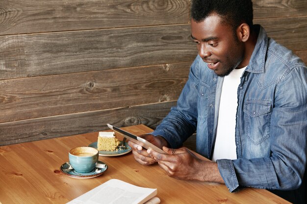 Élégant jeune homme assis dans un café avec tablette