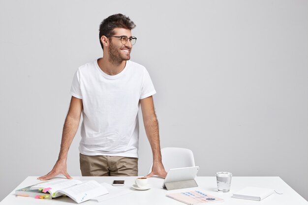 Élégant jeune homme debout près du bureau