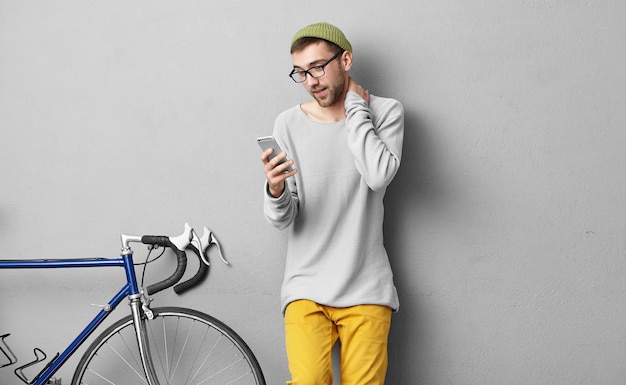 Élégant jeune homme debout près de vélo