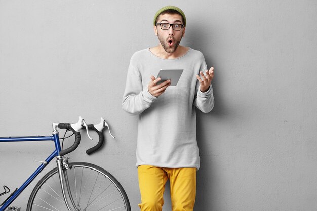 Élégant jeune homme debout près de vélo