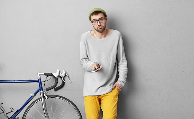 Élégant jeune homme debout près de vélo