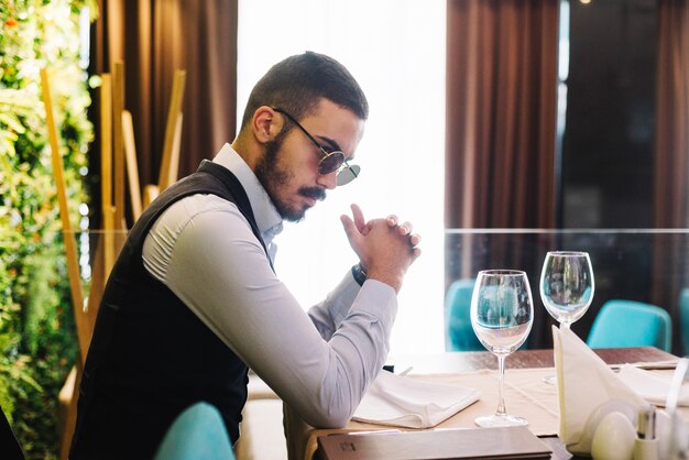 Élégant jeune homme à table au restaurant