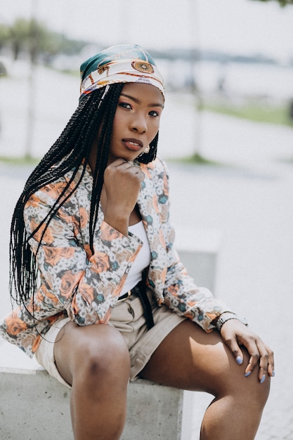 Élégante femme afro-américaine assise sur un rocher dans le parc