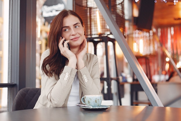 Élégante femme assise à la table avec un téléphone