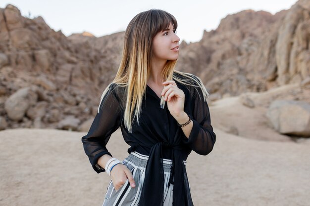 Élégante femme brune posant dans les dunes de sable du désert égyptien.