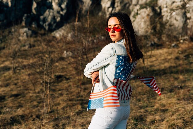 Élégante femme debout sur la nature avec des drapeaux des États-Unis