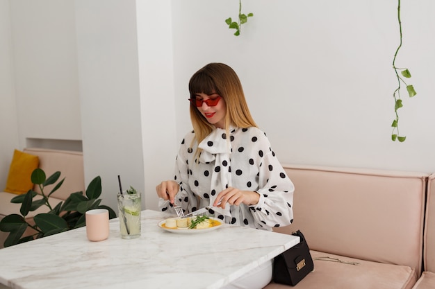 Élégante femme heureuse, manger le petit déjeuner au café