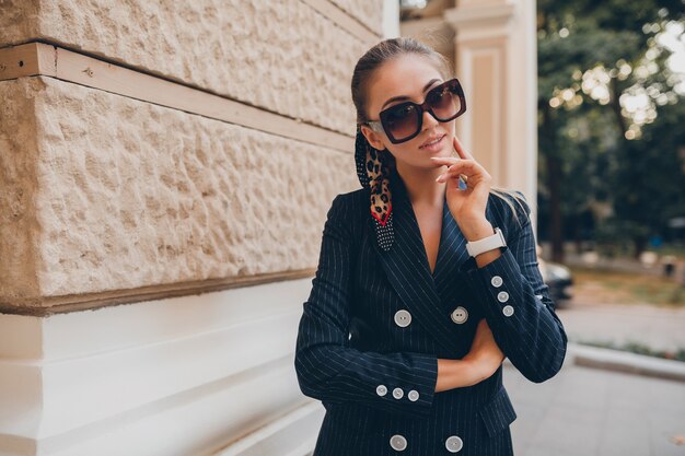 Élégante femme sexy vêtue d'un costume de smoking élégant marchant dans la ville le jour du printemps d'été