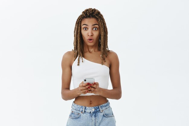Élégante fille afro-américaine moderne à l'aide de smartphone