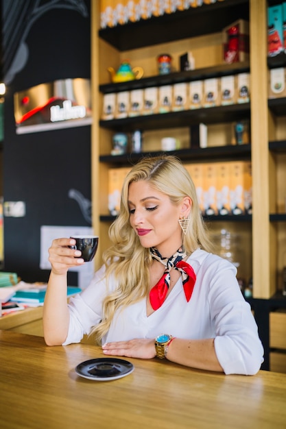 Élégante jeune femme appréciant le thé au café