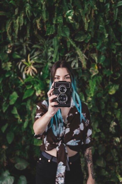 Élégante jeune femme photographiant avec un appareil photo à l&#39;ancienne