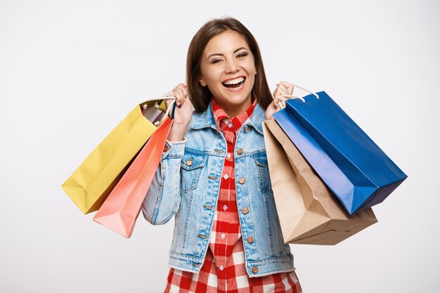 Élégante jeune femme posant avec des sacs à provisions après de grands achats