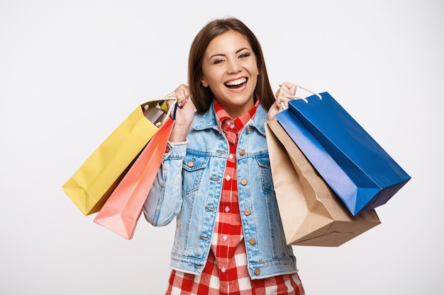 Élégante jeune femme posant avec des sacs à provisions après de grands achats