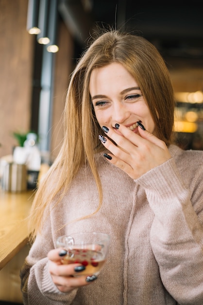 Élégante jeune femme qui rit avec une tasse de boisson au café