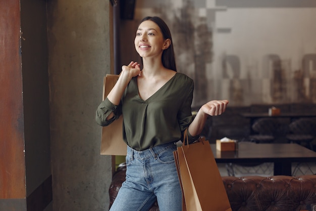 Élégante jeune fille debout dans un café avec des sacs à provisions