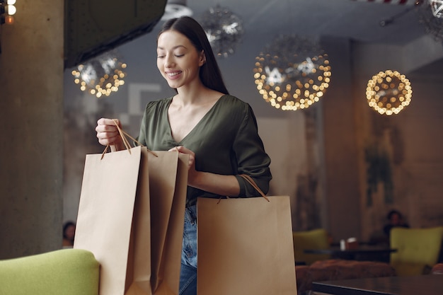 Élégante jeune fille debout dans un café avec des sacs à provisions