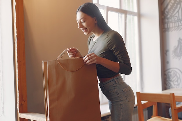 Élégante jeune fille debout dans un café avec des sacs à provisions