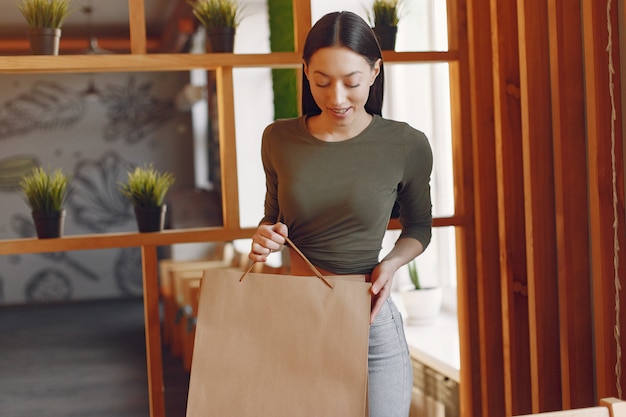 Élégante jeune fille debout dans un café avec des sacs à provisions