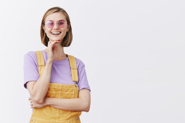 Élégante jolie jeune femme à lunettes de soleil et vêtements d'été à la recherche insouciante, souriant heureux