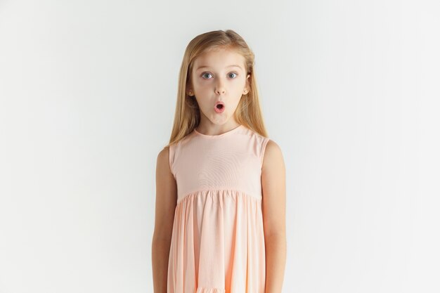 Élégante petite fille souriante qui pose en robe isolée sur studio blanc