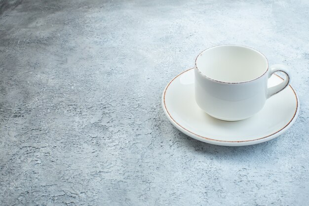 Élégante tasse blanche vide et sauce sur le côté gauche sur une surface grise isolée avec une surface en détresse