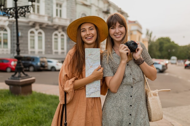 Élégantes jeunes femmes voyageant ensemble en Europe vêtues de robes et d'accessoires à la mode du printemps